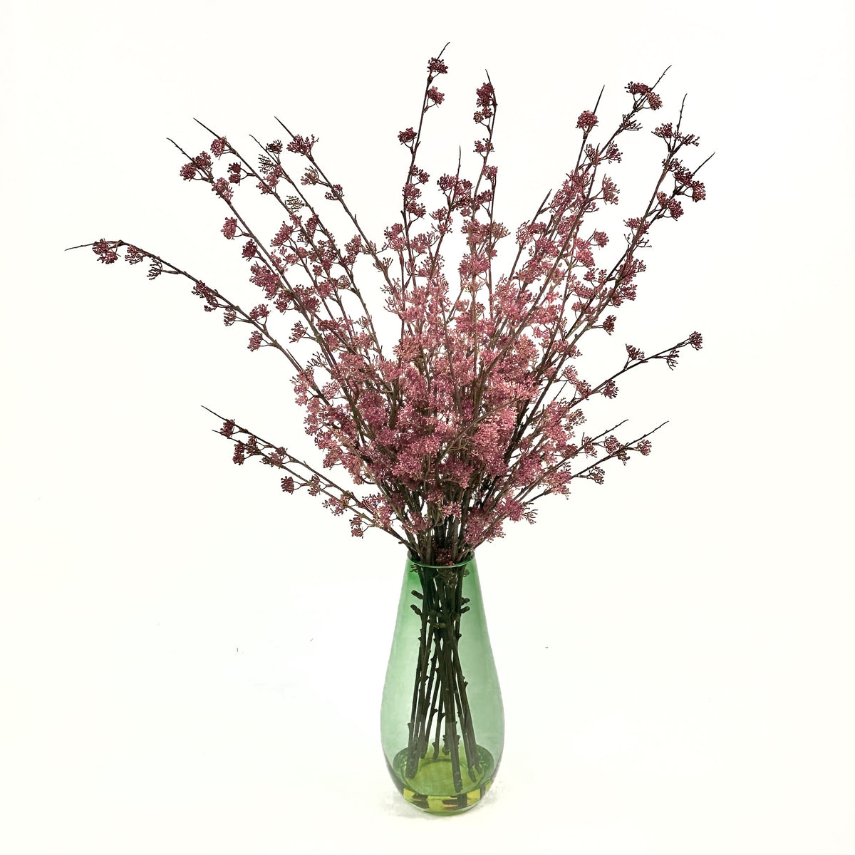 an arrangement of Berry Sprays in a vibrant pink and purple all inside a green shaded glass vase
